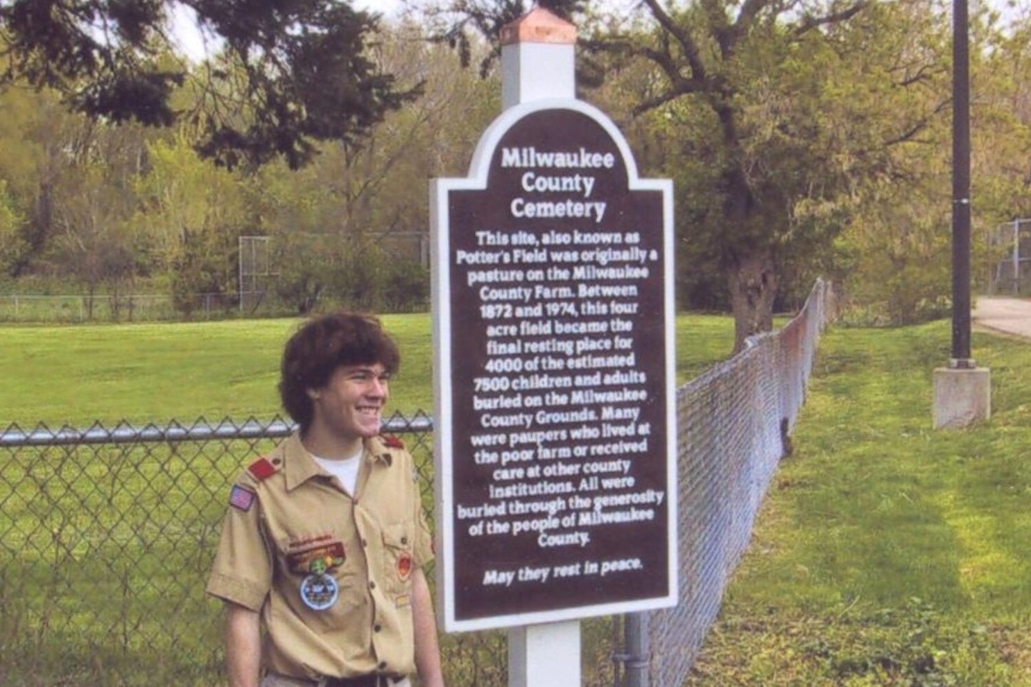 Benjamin Neumann in a Boy Scout uniform posing with a newly installed memorial marker.